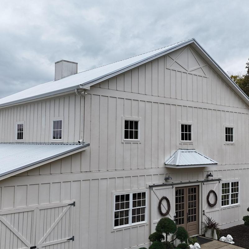 Metal roof hail damage inspection on large barn building