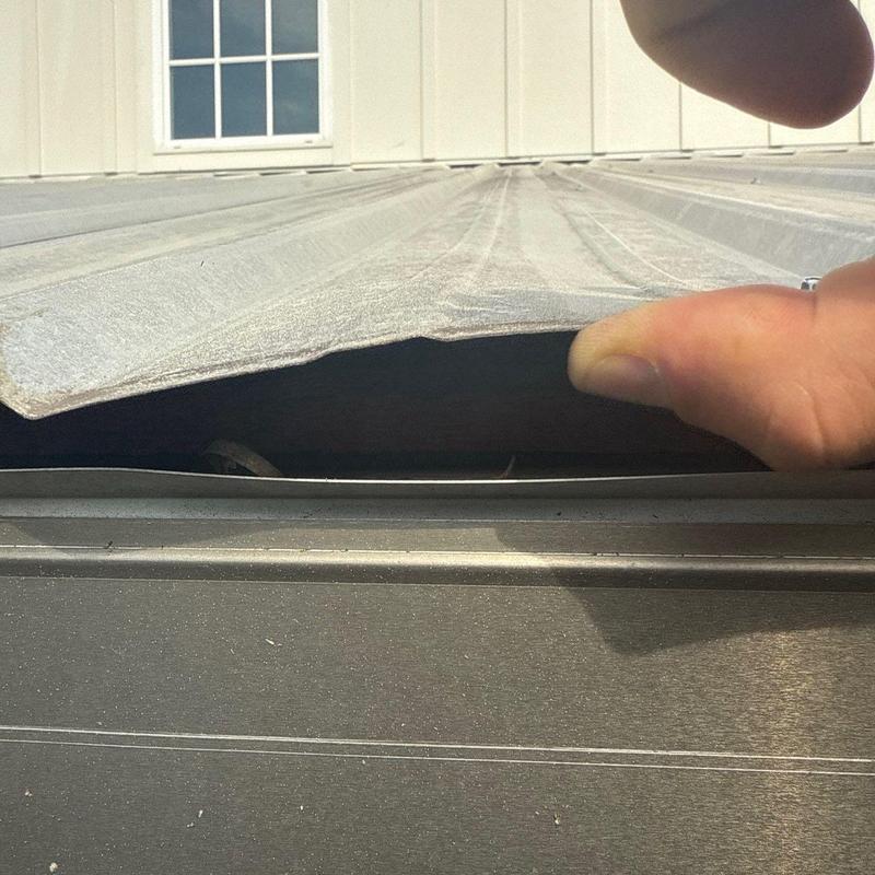 Metal roof panel inspection showing lifted section