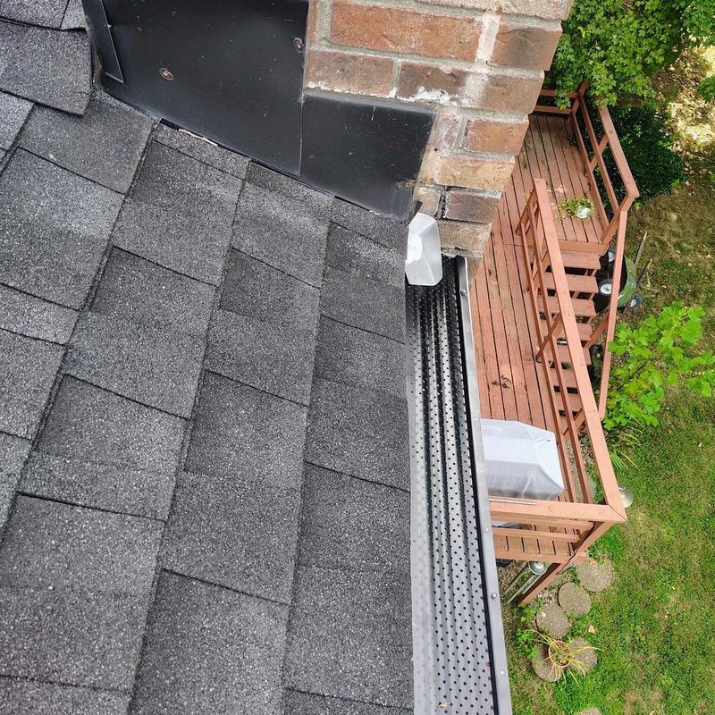 Asphalt shingle roof and gutter guard near brick chimney