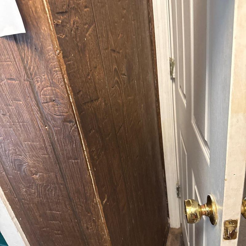 Door latch and damaged wood paneling near frame