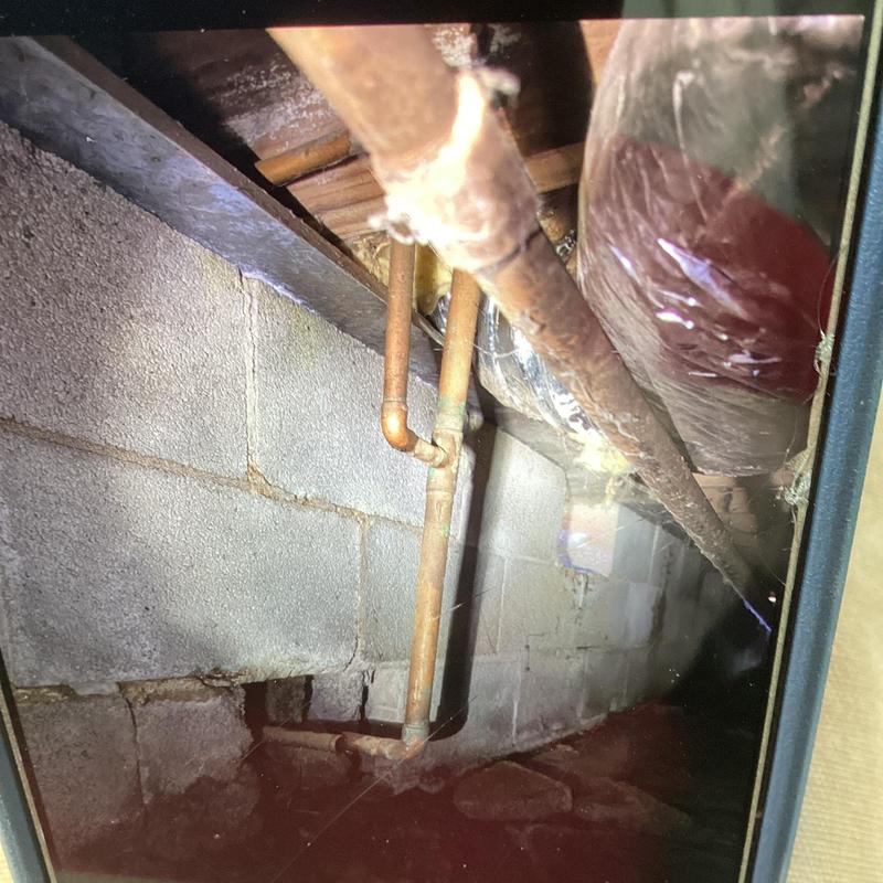 Copper water pipes and brick wall in crawl space