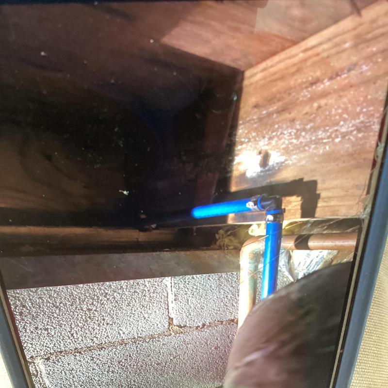 Blue water supply pipe with repaired tee fitting in crawl space