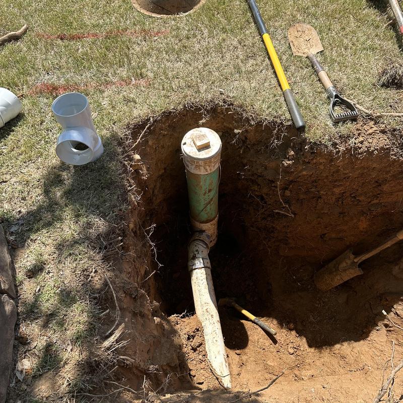 Sewer main cleanout pipe in yard with tools nearby