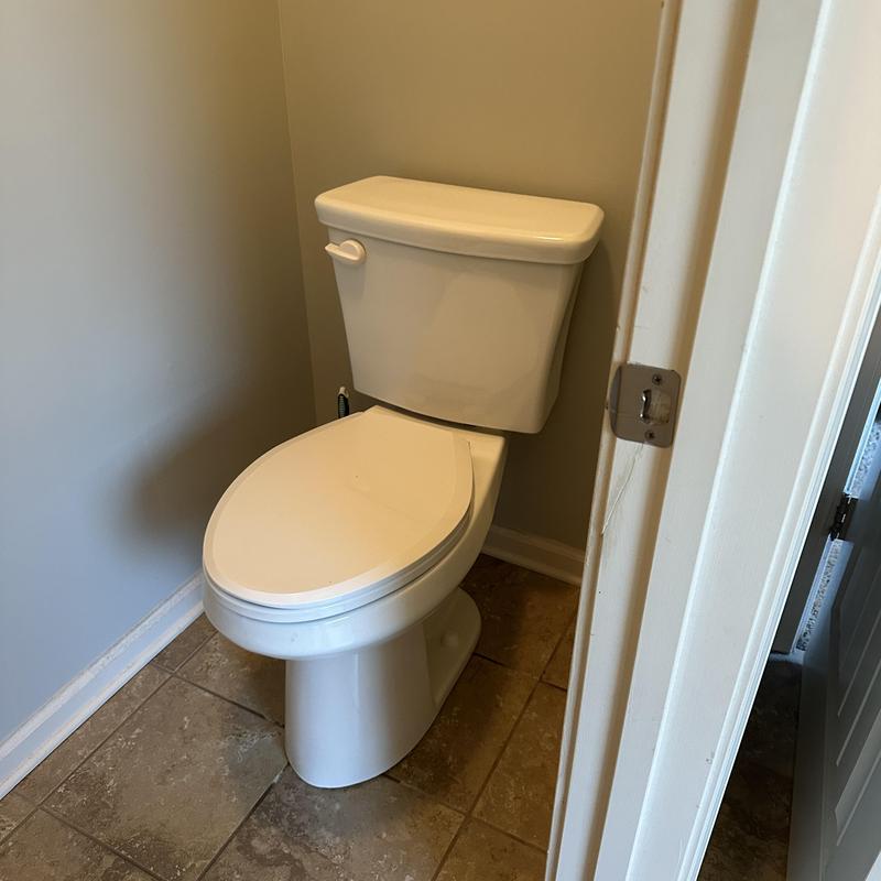 Toilet installation in bathroom corner with tile floor