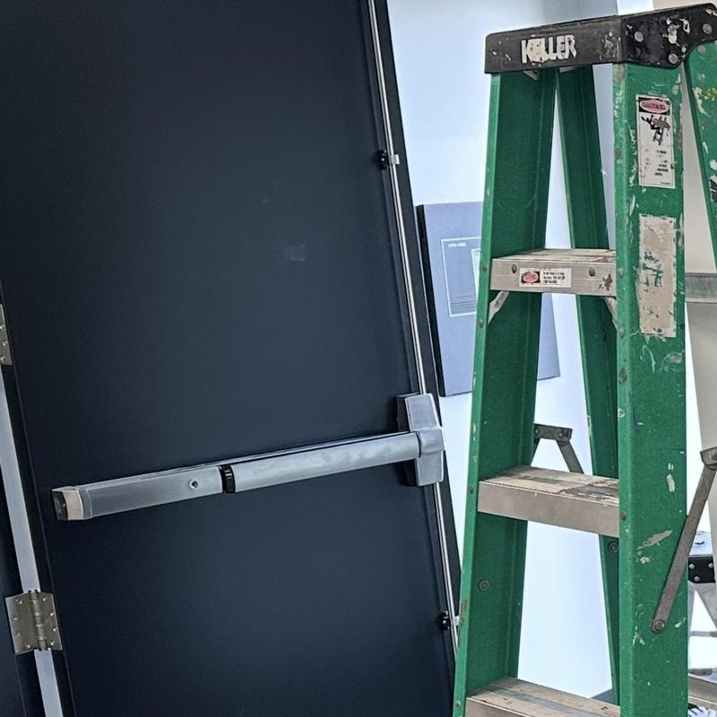 Commercial panic bar door with ladder nearby