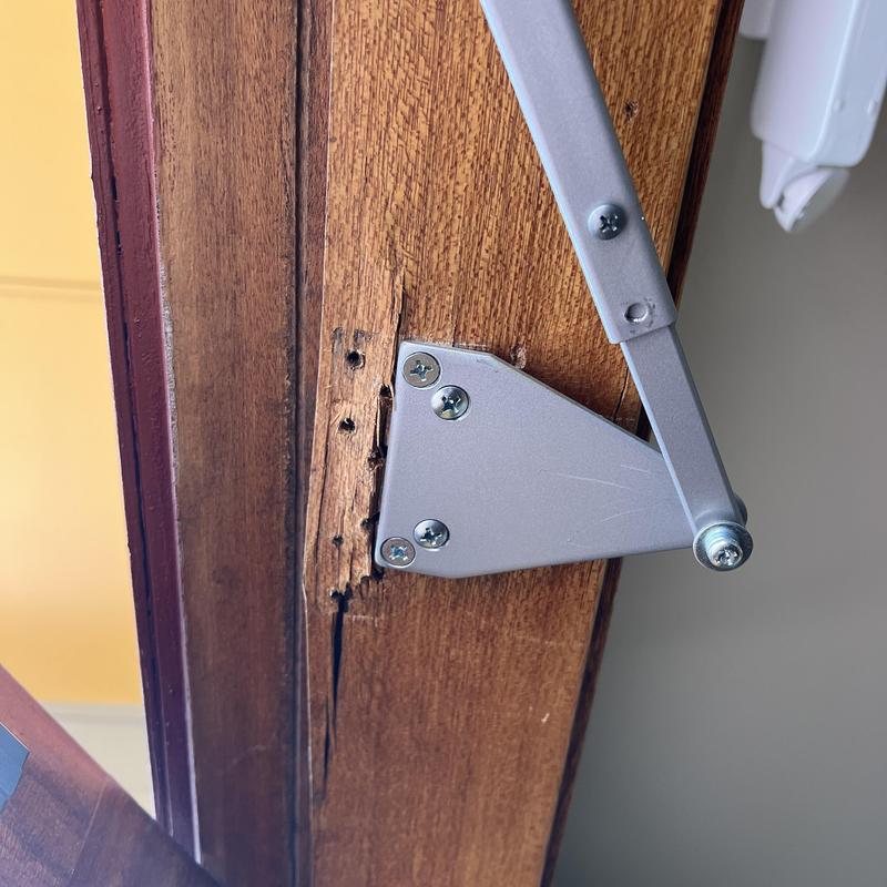 Door closer with metal reinforcement plate on damaged wood frame