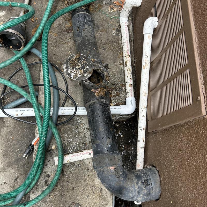Roof drain pipe with grease blockage and hoses nearby