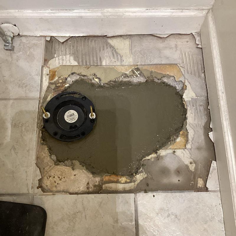 Toilet flange and concrete patch in floor cavity