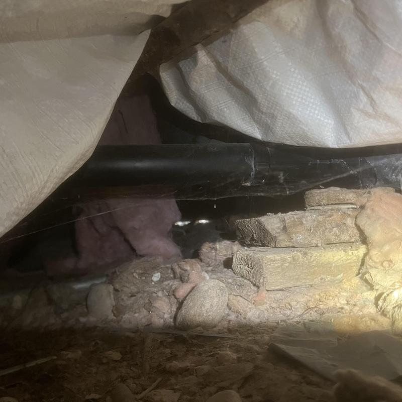 Kitchen sink drain pipe inspected under crawlspace dirt