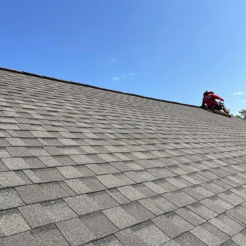 Architectural shingle roof installation with worker on Pearland home
