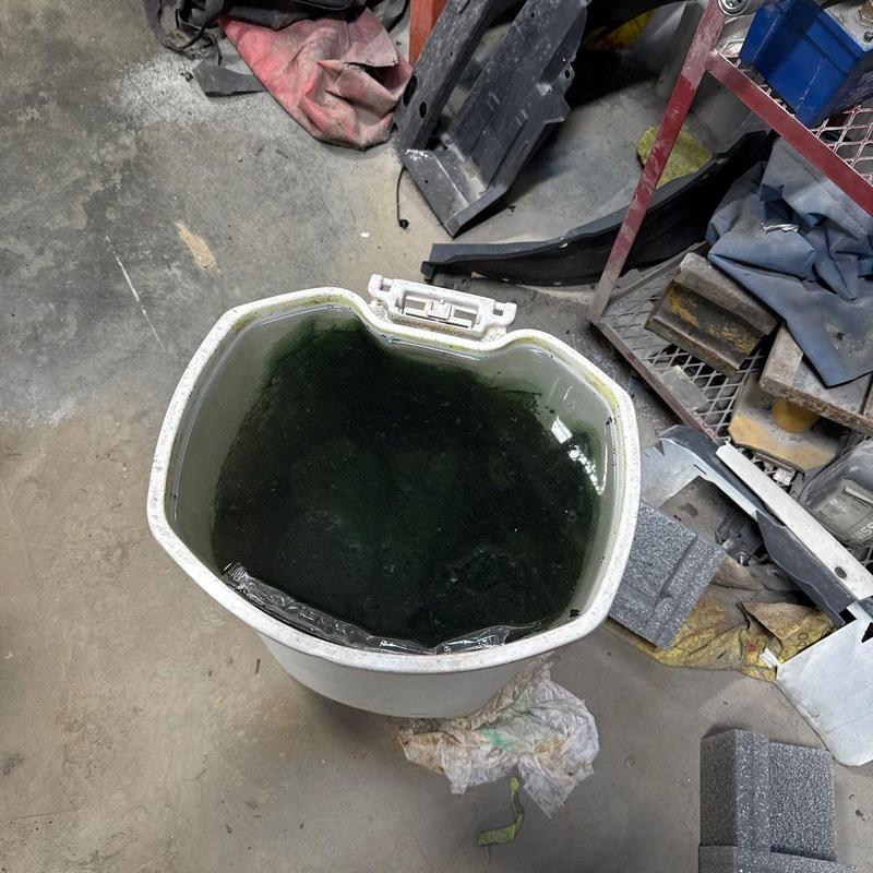 Water container with dark liquid in workshop area