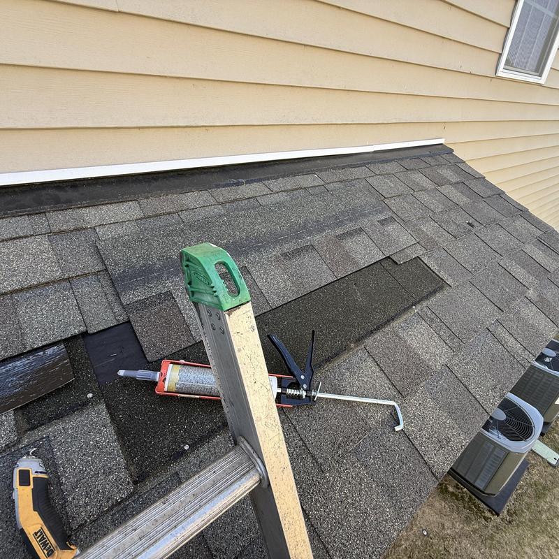 Roof shingles with caulking gun and ladder on small roof slope
