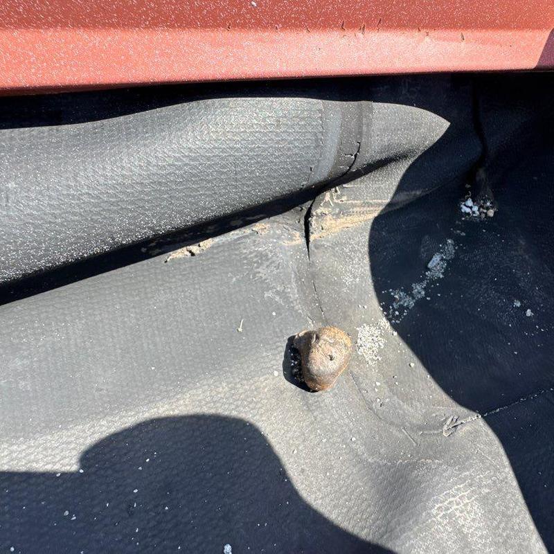 Rubber roof membrane with visible damage and debris