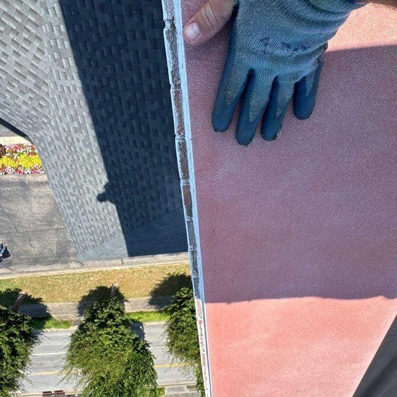 Roof edge with hail damage inspection and glove hand visible