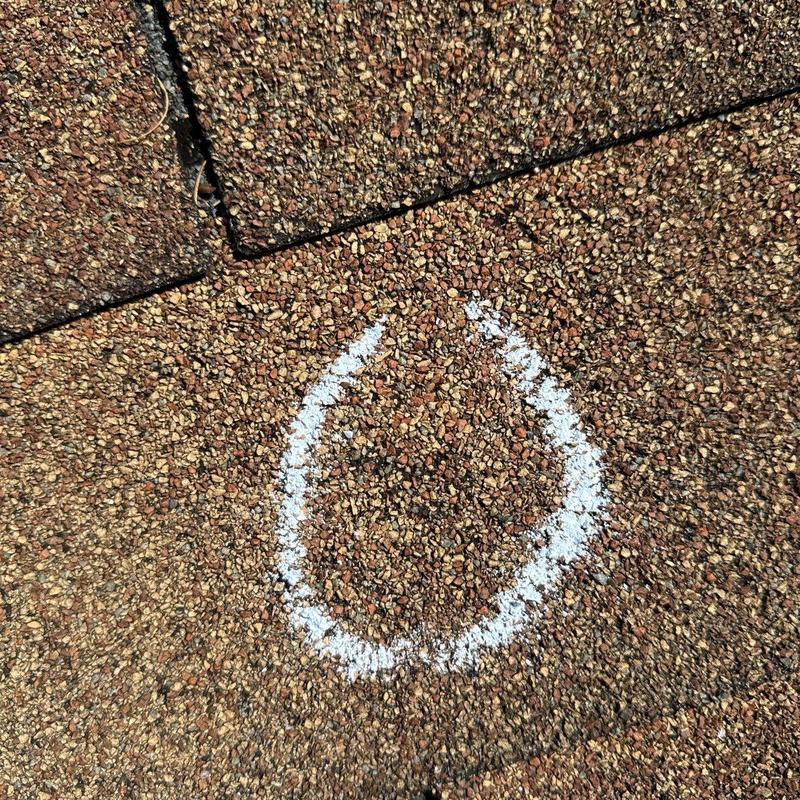 Roof shingles hail damage marked with chalk circle