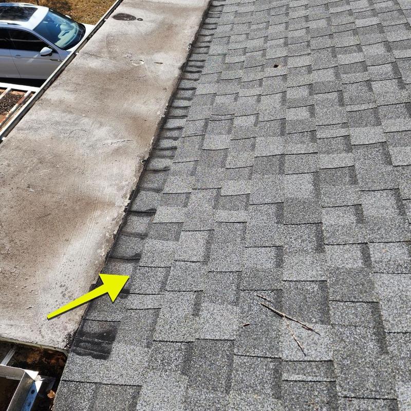 Asphalt roof shingles next to flat roof edge with arrow Asphalt roof shingles next to flat roof edge with arrow