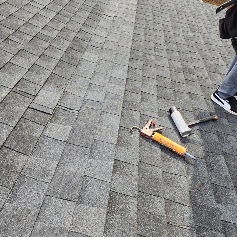 Asphalt shingles on roof with caulking gun and sealant Asphalt shingles on roof with caulking gun and sealant