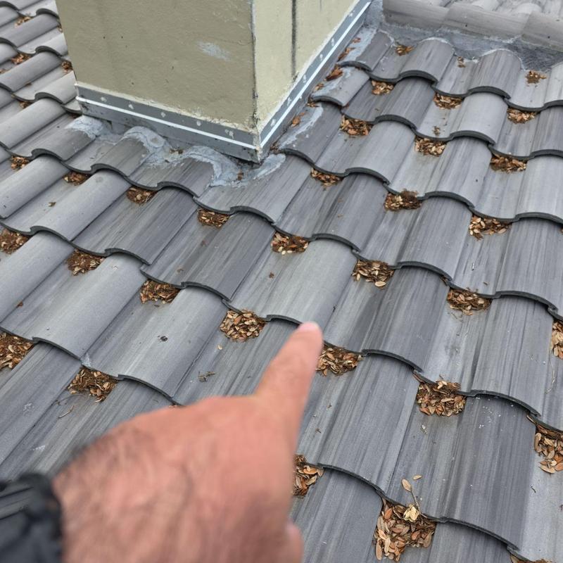 Tile roof near chimney flashing with debris buildup
