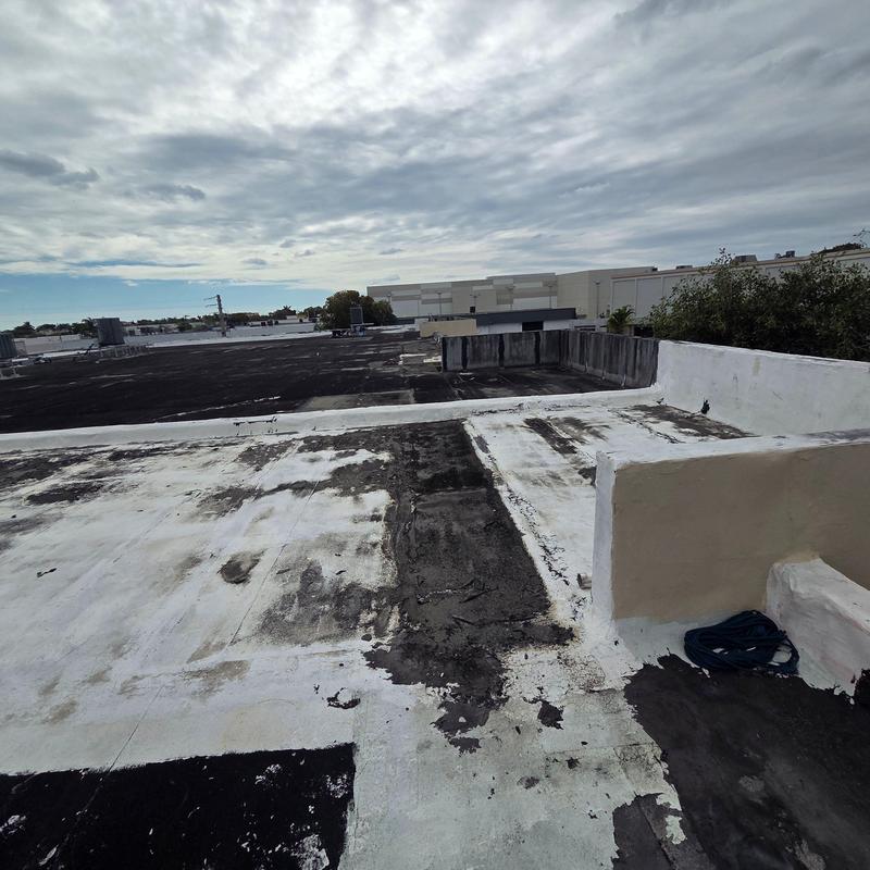 Flat commercial roof with worn patch and repairs Flat commercial roof with worn patch and repairs