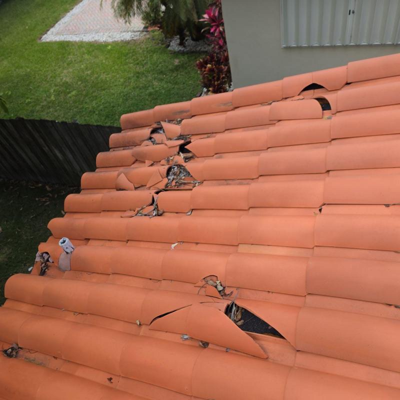 Broken clay tile roof with multiple damaged tiles