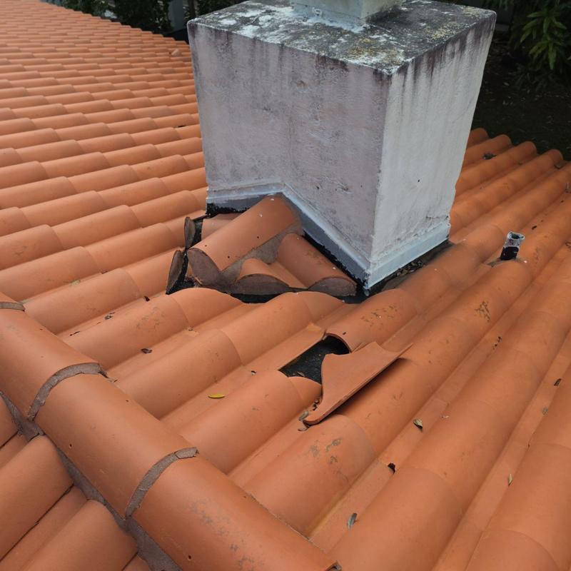 Tile roof around chimney with broken tiles and damage