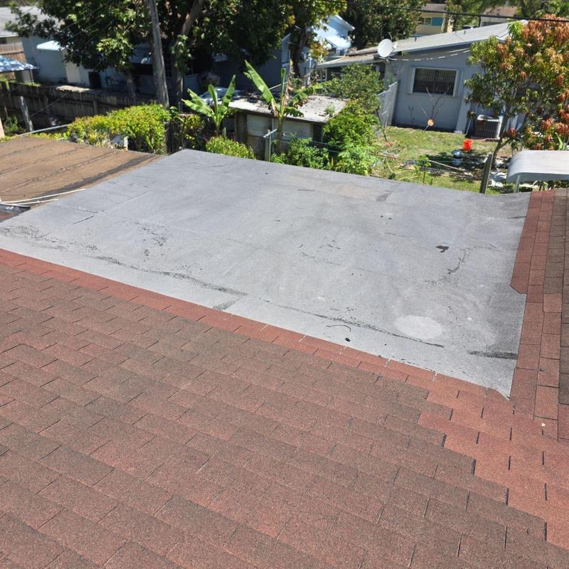 Flat roof and shingle roof junction with wear marks