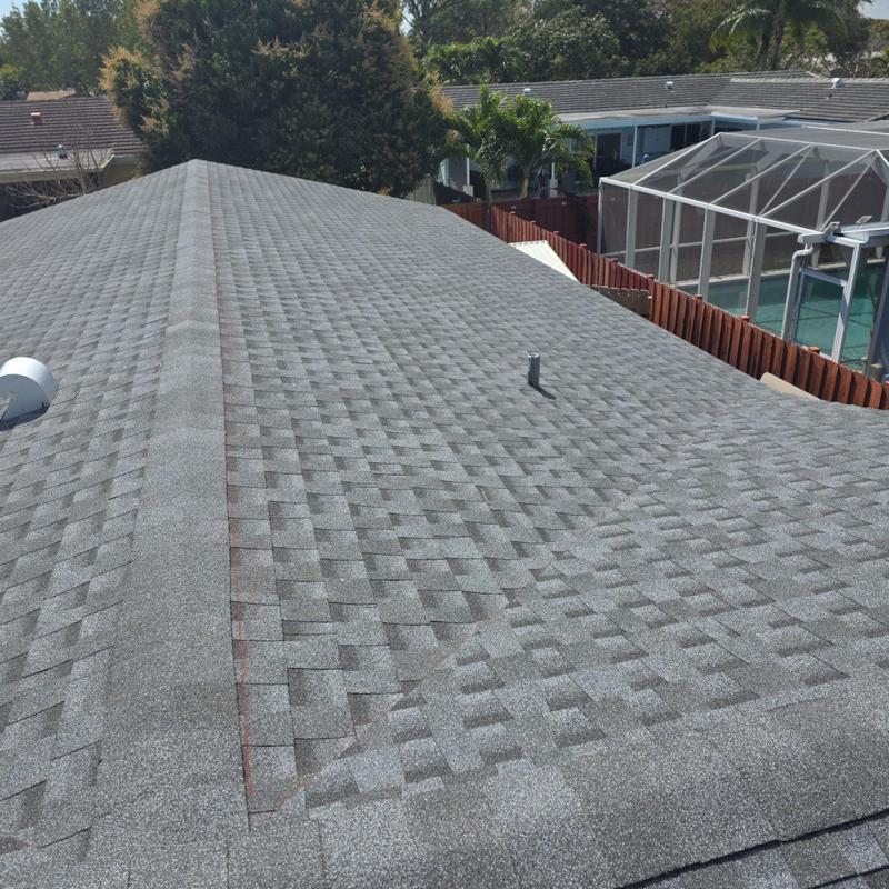 Gray asphalt shingle roof with vent pipes and ridge cap