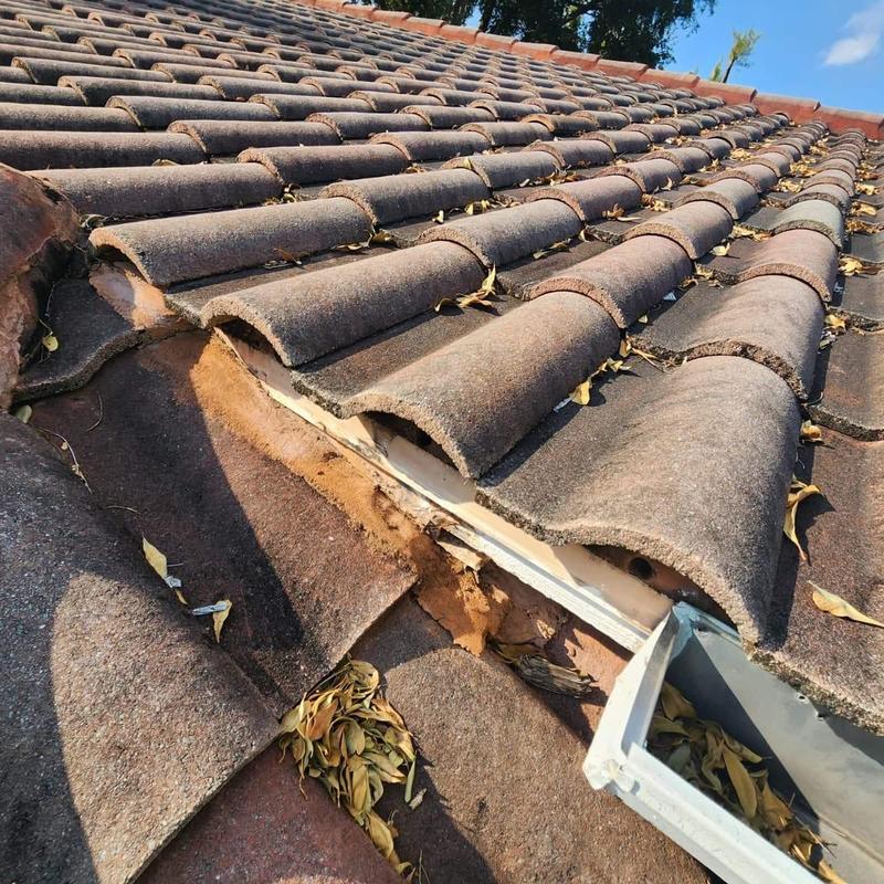 Concrete tile roof with damaged ridge cap and debris