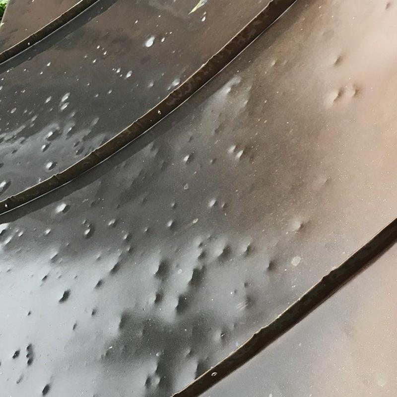 Metal roof panels with hail damage dents close-up