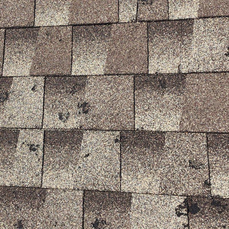 Hail-damaged asphalt roof shingles close-up