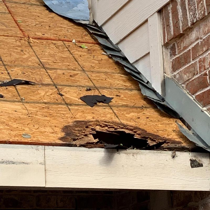 Rotted roof decking damage near side wall and brick facade