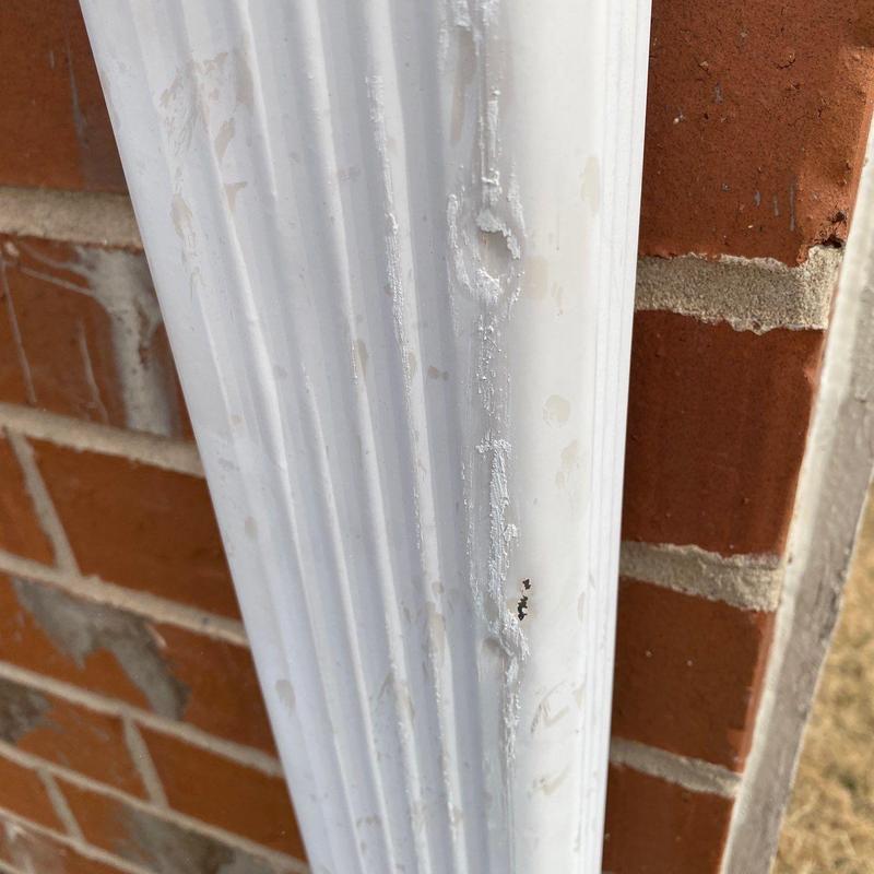 White metal gutter with hail damage close-up