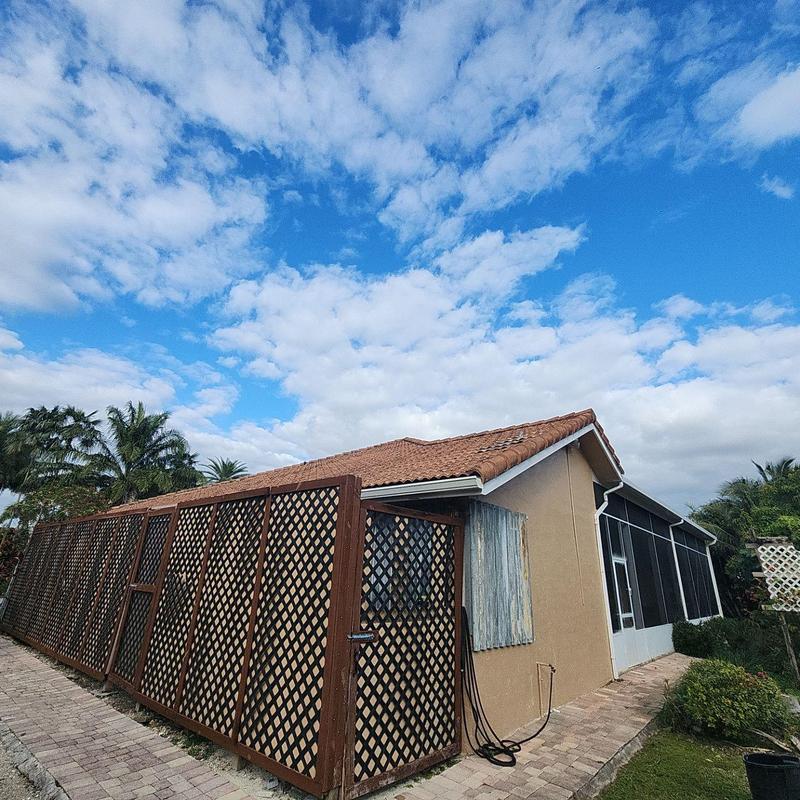 Tile roof with wooden lattice privacy fence under blue sky