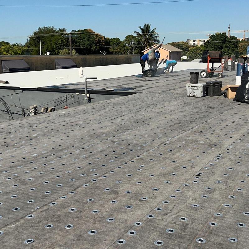 Commercial flat roof membrane installation with workers Commercial flat roof membrane installation with workers
