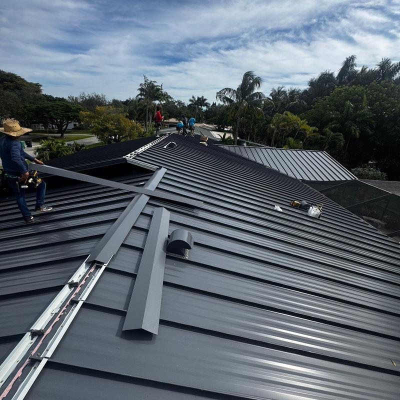 Standing seam metal roof installation with workers on site