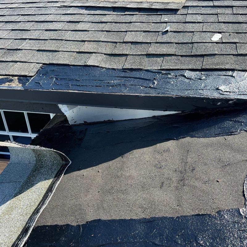 Shingle roof with damaged and patched flashing area
