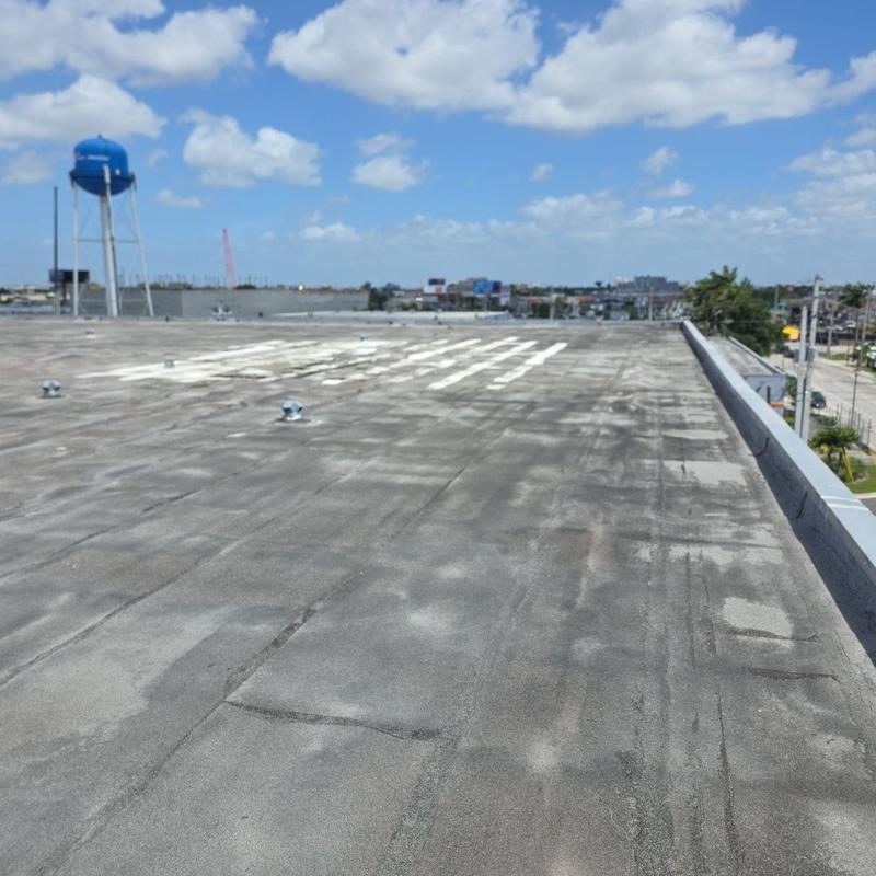 Commercial flat roof with worn patches under blue sky Commercial flat roof with worn patches under blue sky