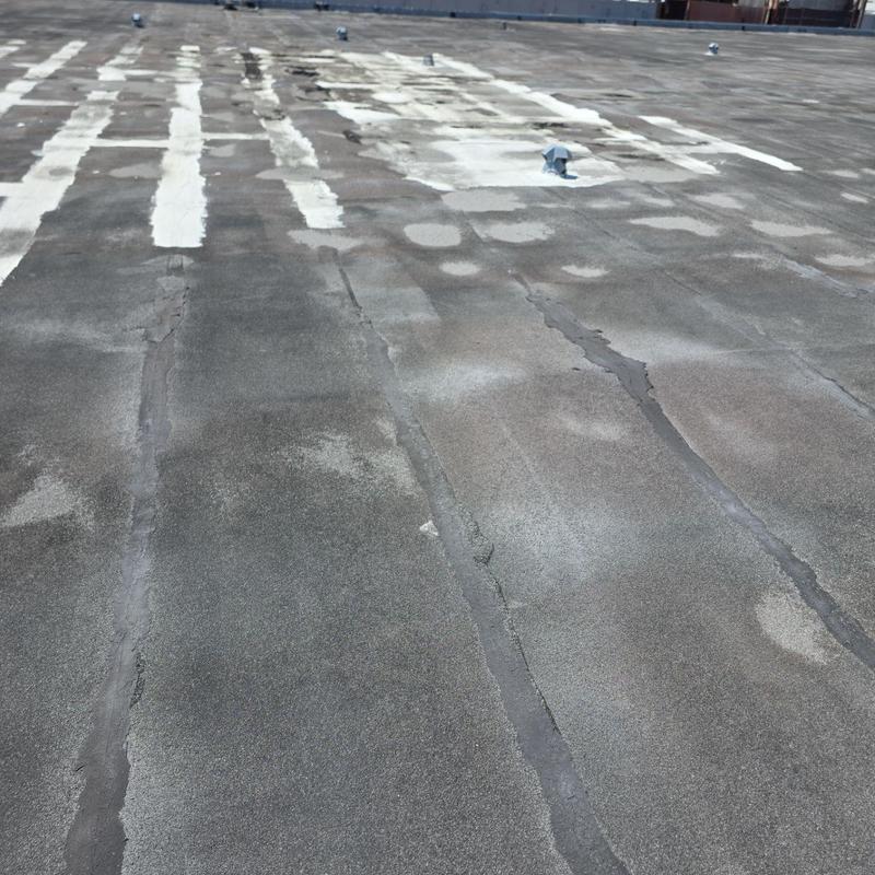 Commercial flat roof with patch repairs and sealant lines Commercial flat roof with patch repairs and sealant lines