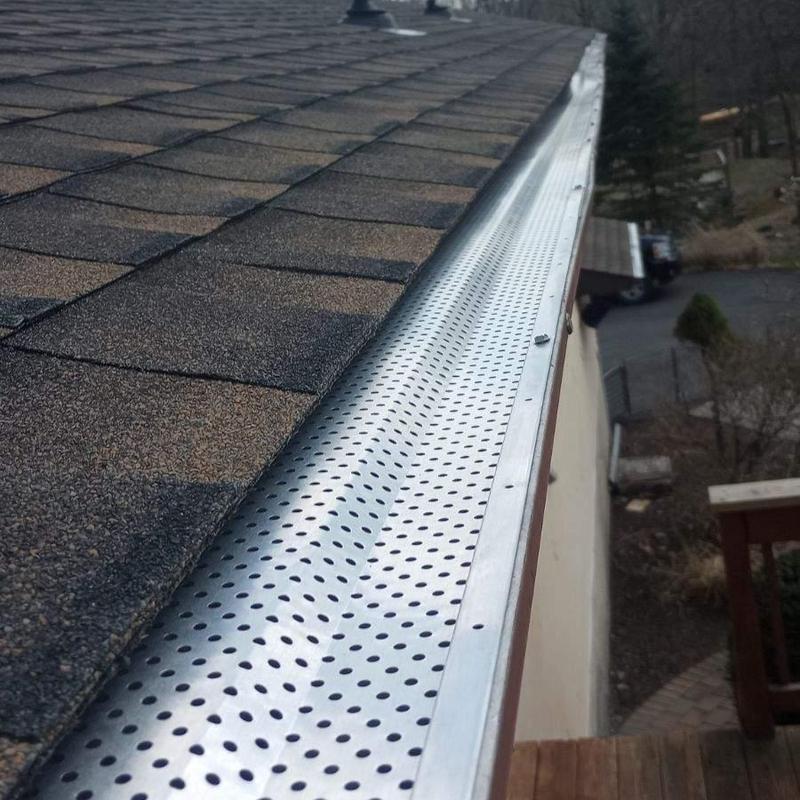 Perforated metal gutter guard on shingle roof edge Perforated metal gutter guard on shingle roof edge
