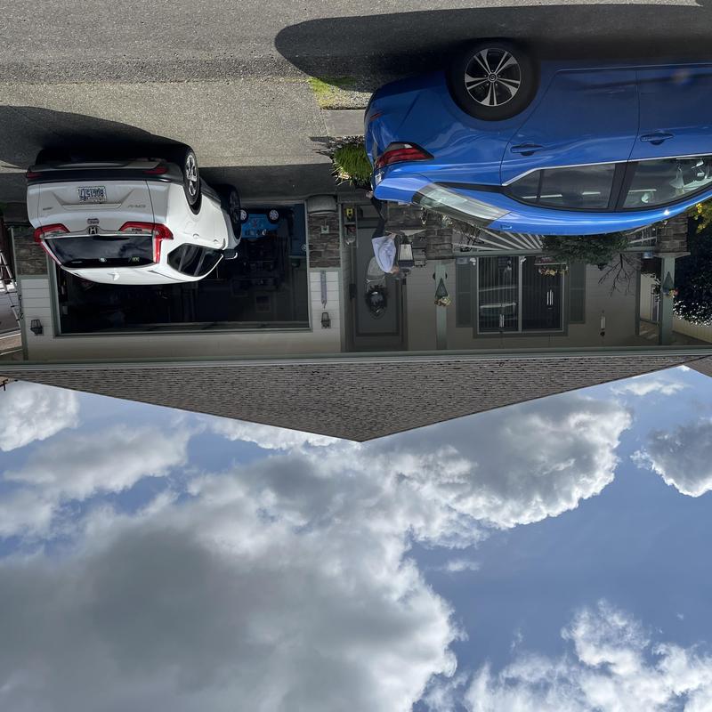 Asphalt shingle roof with clear sky above two parked cars