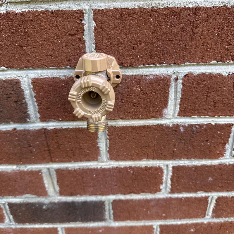 Frost proof hose bib installed on exterior brick wall