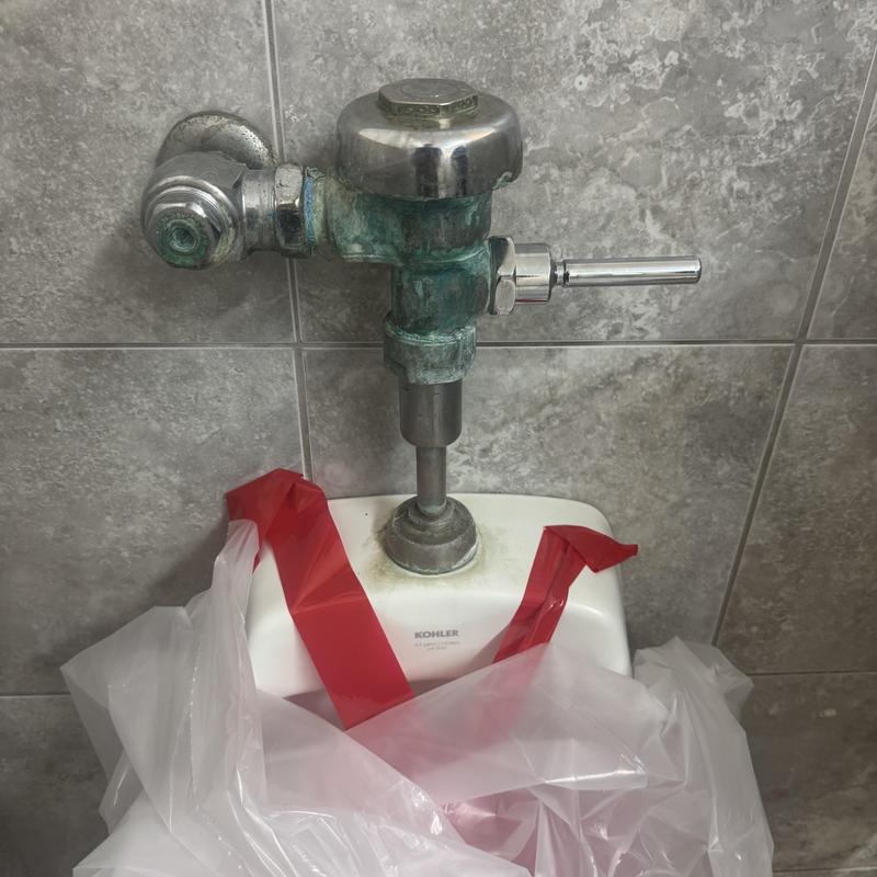 Urinal flush valve with corroded pipes and taped off bowl Urinal flush valve with corroded pipes and taped off bowl