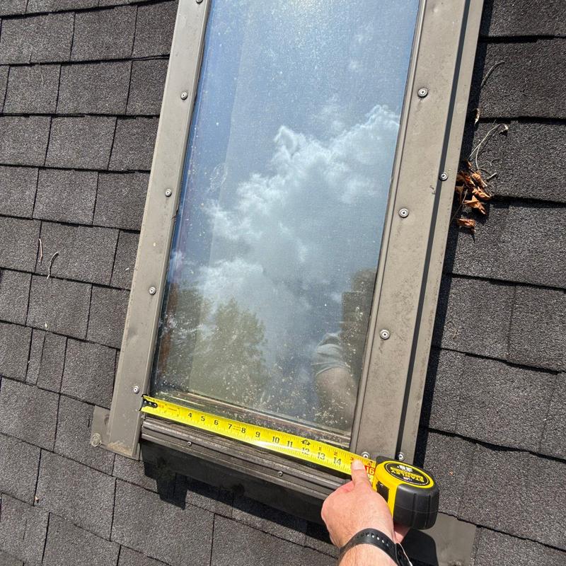 Skylight on asphalt shingle roof with tape measure
