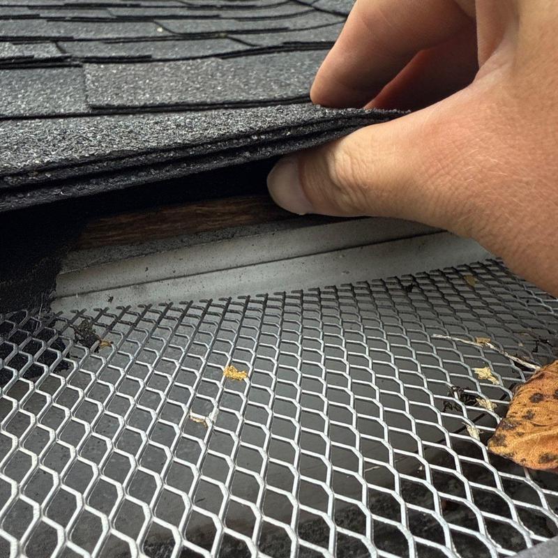 Roof shingles lifted to inspect hail damage and mesh screen