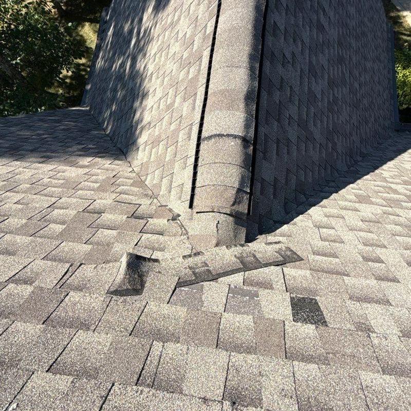 Asphalt shingle roof with visible hail damage near ridge cap