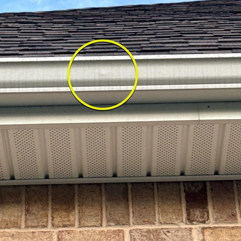 Gutter with dented section circled on home exterior