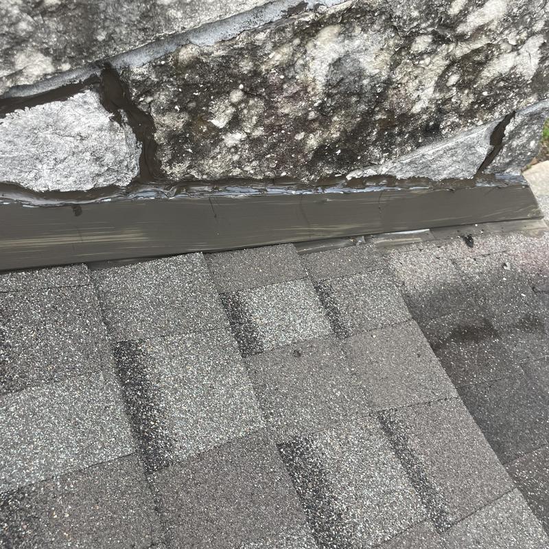 Step flashing sealing on shingle roof next to stone wall Step flashing sealing on shingle roof next to stone wall