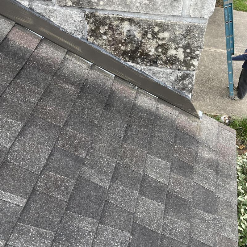 Step flashing on residential shingle roof near stone chimney Step flashing on residential shingle roof near stone chimney