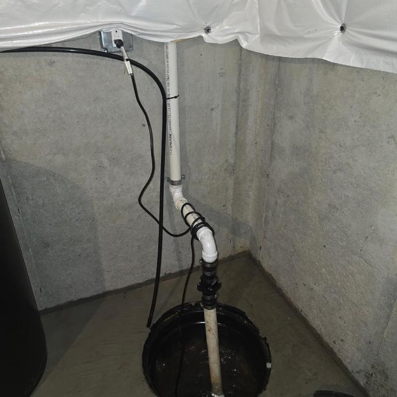 Cast iron sump pump with PVC discharge pipe in basement