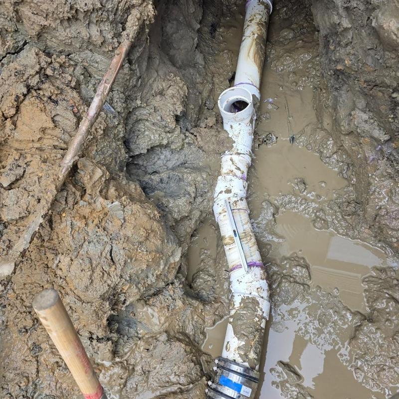 Sewer pipe in muddy trench with pitch level gauge